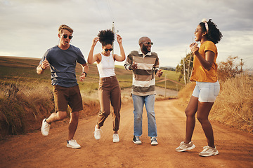 Image showing Friends dance, travel and freedom adventure on a nature dirt road jump for fun and joy outdoor. Diversity of people and travelers happy about free and summer holiday laughing together in desert