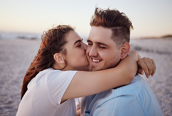 Image showing Love, couple and kiss on beach happy to celebrate relationship with sunset being relax, smile and on holiday. Romance, man and woman hug, embrace and bonding on seaside vacation together outdoor.