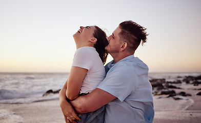 Image showing Sunset, love and young couple on the beach bonding, laughing and enjoying their honeymoon holiday. Happy, fun and man embracing and playing with woman while on romantic vacation in Miami Florida.