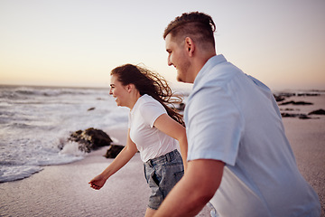 Image showing Love, beach and couple holding hands running to the water on a romantic sunset evening together outdoors in nature. Smile, romance and happy woman on honeymoon vacation with an excited partner at sea