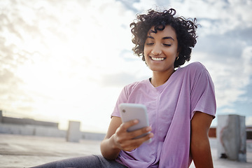 Image showing Phone, social media and communication with a woman in the city on a rooftop, sending or writing a message against a blue sky background. 5g mobile technology, networking and text with a young female