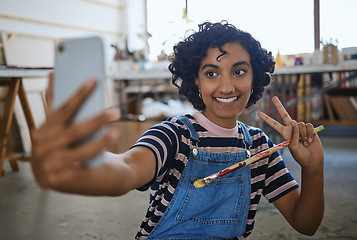Image showing Indian woman artist, selfie with paint brush and art on floor of studio workshop to share to social media. Portrait of happy, creative professional painter and smiling after oil or watercolor project