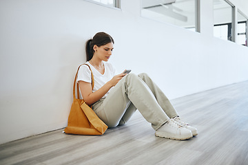 Image showing Sad university woman, student alone on the floor in the hallway after class or lecture and browsing social media on smartphone. Academic depression, stress and anxiety from college education pressure