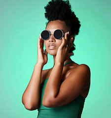 Image showing Fashion, black woman and glasses with a model in studio on a green background with vintage or retro sunglasses or eyewear. Trendy, style and confident with a young african american female with afro