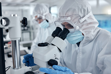 Image showing PPE, covid and DNA scientist with microscope research for science innovation, investigation and development in a test laboratory. Biotechnology people with analysis or studying medical sample in lab