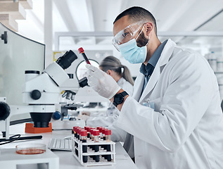 Image showing Scientist doing research for covid using a microscope and test tube in a lab. Healthcare worker in biotechnology, medicine and analytics testing liquid in science laboratory for blood sample results