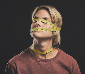 Image showing Face, tape measure and stress with an anorexia woman in studio on a dark background for mental health and eating disorder. Sick, hunger and weight with a female struggling with society body pressure