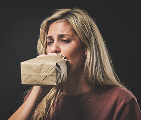 Image showing Anxiety, scared woman breathing into paper bag on dark background for mental health or psychology mockup. Young girl experience fear, panic or asthma attack breathe air for stress, sad and depression