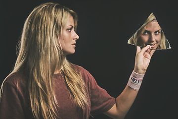 Image showing Suicide, mental health and mirror with a woman looking at her reflection in a piece of glass in studio on a dark background. Bipolar, schizophrenia and depression with a sick female going mad