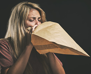 Image showing Anxiety, breathing and scared woman with paper bag, mental health and emergency oxygen air for lungs on black background. Panic attack breathe problem, stress and fear of depression, nausea and sick