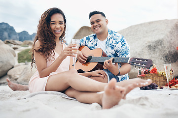 Image showing Couple, beach and guitar for music and love on picnic together on sand by ocean. Man, woman and smile with happiness on face with food, champagne and flowers to relax, vacation and travel in summer