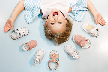 Image showing Child, shoes and head above floor with smile on face against blue backdrop. Girl, happy and sandal in mockup excited with happiness, color and summer fashion against studio background in Sweden