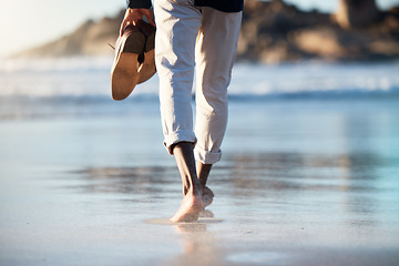 Image showing Man, beach and walking feet in water in summer with shoes in hand to relax, breathe and thinking. Ocean, walk and sunshine for mindfulness, calm and peace at sea, nature and outdoor in Cape Town