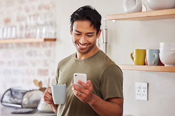 Image showing Phone, coffee and social media with a man in his kitchen in the morning while reading a message in his home. Mobile, internet and tea with a handsome young man sending a text from his house in India