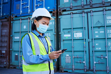 Image showing Covid, social media and logistics worker reading chat on a phone working at a container factory. Asian industrial employee with face mask on web for shipping and delivery of cargo on mobile at a site