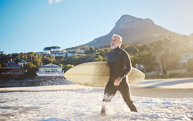 Image showing Beach, surfing and senior man with a surfboard walking in the ocean water for training on vacation. Adventure, exercise and elderly surfer in the sea while on a retirement holiday in Bali Indonesia.