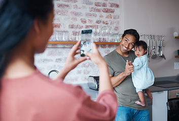 Image showing Family, care and mother with phone for photo of father and baby with down syndrome in the living room of their house. Mom taking a picture of a happy dad and child with special needs on a smartphone