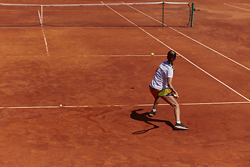 Image showing A young girl showing professional tennis skills in a competitive match on a sunny day, surrounded by the modern aesthetics of a tennis court.