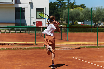 Image showing A young girl showing professional tennis skills in a competitive match on a sunny day, surrounded by the modern aesthetics of a tennis court.