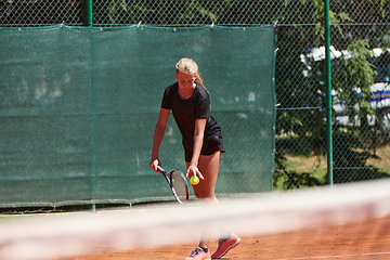 Image showing A young girl showing professional tennis skills in a competitive match on a sunny day, surrounded by the modern aesthetics of a tennis court.