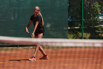 Image showing A young girl showing professional tennis skills in a competitive match on a sunny day, surrounded by the modern aesthetics of a tennis court.