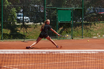 Image showing A young girl showing professional tennis skills in a competitive match on a sunny day, surrounded by the modern aesthetics of a tennis court.