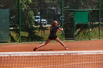 Image showing A young girl showing professional tennis skills in a competitive match on a sunny day, surrounded by the modern aesthetics of a tennis court.