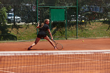 Image showing A young girl showing professional tennis skills in a competitive match on a sunny day, surrounded by the modern aesthetics of a tennis court.