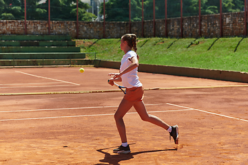 Image showing A young girl showing professional tennis skills in a competitive match on a sunny day, surrounded by the modern aesthetics of a tennis court.