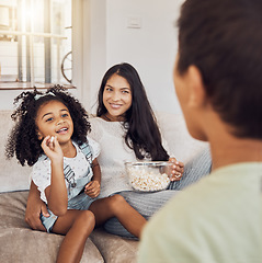Image showing Mother, family and girl throw popcorn on sofa in home living room. Love, relax and child or kid with parents feeding food to person, spending time together and bonding in house having fun playing.