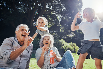 Image showing Grandparents, bubbles and children play in park happy together for fun, joy and outdoor happiness. Retired, smile and excited elderly senior couple, girl grandkids and love playing outside in nature