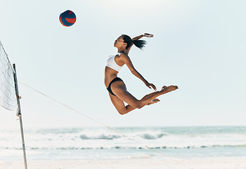 Image showing Sports woman jump at volleyball beach summer outdoor competition game on ocean or sea sand playing to win. Healthy, fitness and training agile girl or young athlete ready hit ball over net in match