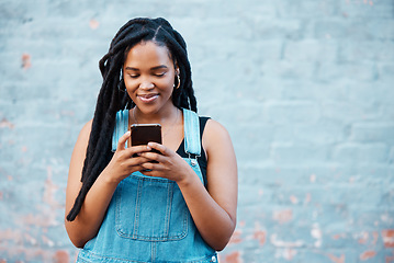 Image showing Happy black woman typing on smartphone on social media marketing, advertising or mobile app on blue wall background mockup. Gen z teenager with cellphone networking, online chat or check notification