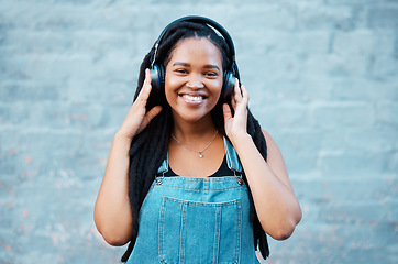 Image showing Gen z black woman, music headphones and portrait on wall background in Nigeria city listening to radio, audio and sound. Happy young african girl student, freedom and streaming urban outdoor podcast