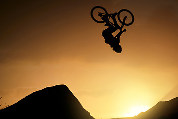 Image showing Cyclist, fitness and stunt jump at sunset in Colorado countryside nature mountains in fitness, exercise or training. Danger risk, extreme sports mountain bike or freedom man in sunrise energy workout
