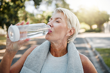 Image showing Senior fitness woman drinking water bottle outdoors after training, running workout and exercise in neighborhood street. Thirsty elderly lady runner hydration rest for cardio wellness or marathon jog
