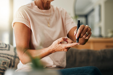 Image showing Healthcare, diabetes and a senior woman using blood sugar test on finger in living room. Health, innovation and daily life of diabetic lady on sofa with glucometer to check glucose level in her home.