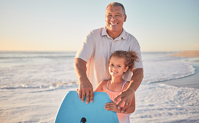 Image showing Beach, grandfather and girl learning to surf from a happy senior man in her family on a summer holiday outdoors. Smile, sports and old man teaching or training a child surfing on a board in the ocean