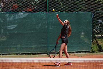 Image showing A young girl showing professional tennis skills in a competitive match on a sunny day, surrounded by the modern aesthetics of a tennis court.