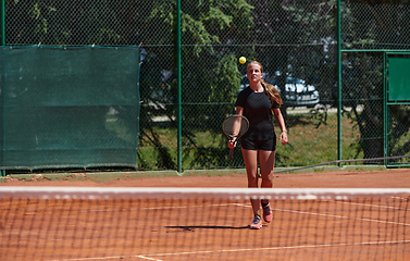 Image showing A young girl showing professional tennis skills in a competitive match on a sunny day, surrounded by the modern aesthetics of a tennis court.