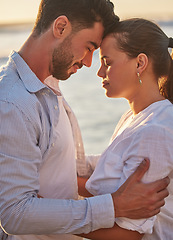Image showing Couple, sunset and beach for love together on holiday or honeymoon. Man, woman and ocean in embrace for romance, during vacation, trip or travel by the sea in late summer sunlight show happiness