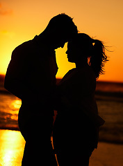 Image showing Silhouette of young couple on the beach at sunset embracing each other in affection. People on holiday, vacation and honeymoon by the ocean. Intimate, love and romantic man and woman together by sea