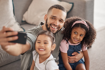 Image showing Father taking a selfie on his phone with his children hugging and bonding in their family home. Multicultural father and daughters smiling, happy and taking a picture on their smartphone together