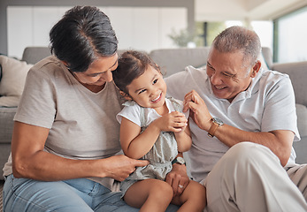 Image showing Grandparents, girl and sofa in house, happy and playing together in bonding time. Grandmother, grandpa and child on couch in living room, smile and fun in family home for visit or holiday in Jakarta