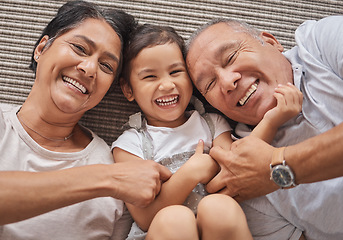 Image showing Kid, grandma and grandpa lying on floor playing at home, spending family time together above view. Happy grandparents bonding with little girl in Mexico. Senior man, elderly woman and child laughing.