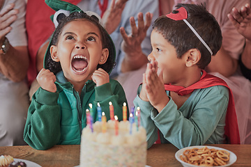 Image showing Happy birthday, party and children in halloween costume to celebrate young and fun girls special day together. Cake, fantasy and excited kid in a dinosaur monster outfit and boy in a superheroes cape