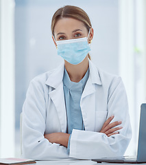 Image showing Face mask, covid and portrait of medical doctor in her office at the hospital during pandemic. Coronavirus, woman and healthcare professional sitting at desk in consultation room at medicare clinic.