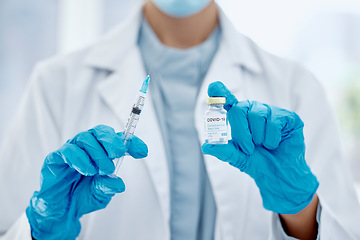 Image showing Covid, vaccine and hands of a medical doctor holding the needle and syringe for an injection. Medicine, science and closeup of healthcare worker with a pharmaceutical virus treatment in a glass vial.