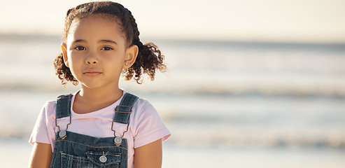 Image showing Portrait of girl child on holiday, at beach and standing in the sun by the ocean. Kid on summer holiday, travel to the coast in the sunshine and sand. Toddler by sea, childhood memory and on vacation
