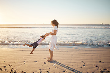 Image showing Mother, girl spinning and family at the beach playing together in the sunshine. Mom and young fun child in summer sunlight bonding at sea water waves and beach sand feeling happy outdoor on vacation